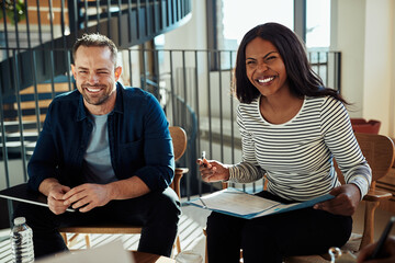 Two laughing businesspeople having a meeting together in an office