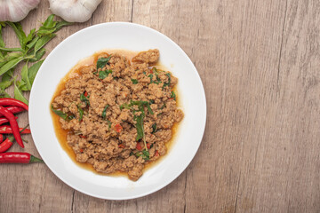 Pad kaprao, minced chicken in white plate on wooden background