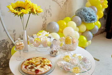 Delicious sweet holiday buffet with cupcakes, meringues and other desserts. Background of balloons