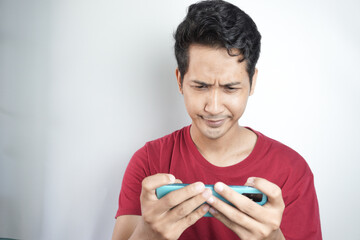 Photo of young man moody anxious play game mobile bite lips failure isolated over white color background
