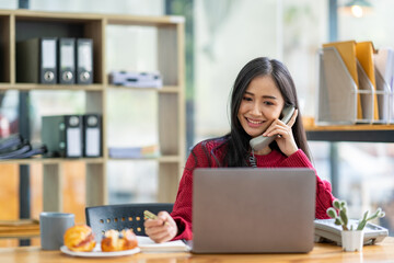 The perspective of an Asian businesswoman Sit and summarize online work orders and finances, so relax at work. By taking a break for coffee and snacks at the office.