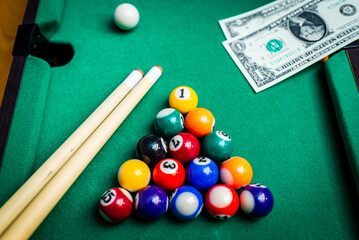 Gambling ardor game.Money and multicolored billiard balls with numbers.Dollar paper banknotes on the game table.Selective focus.