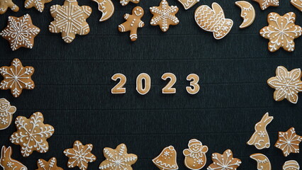 Obraz na płótnie Canvas Cozy Christmas gingerbread frame on a black background and the number 2023 in the middle. Top View. Christmas and a Happy New Year Concept.