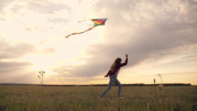 Little girl runs in the park at sunset with a kite. happy child runs through the park plays with a kite. Happy cheerful child concept. A small child is playing at sunset.