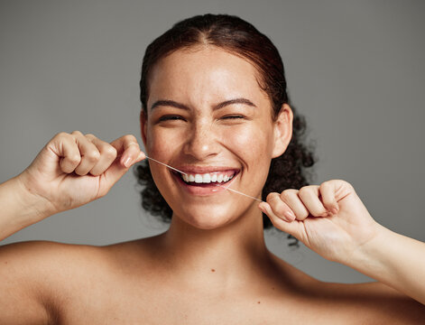 Dental floss, flossing teeth and woman with a smile for oral hygiene, health and wellness on studio background. Face of a happy female during self care, healthcare and grooming for a healthy mouth