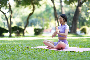 Attractive and strong Asian woman with a beautiful body. meditation relax yoga in an elegant posture in the green park Modern concept of relaxation and health care.