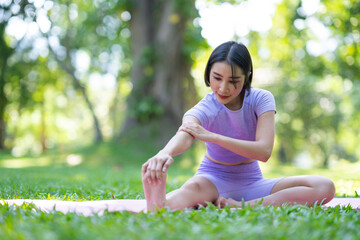 Attractive and strong Asian woman with a beautiful body. yoga in graceful posture in the green park Modern concept of relaxation and health care.