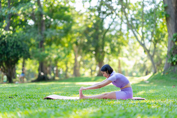Attractive and strong Asian woman with a beautiful body. yoga in graceful posture in the green park Modern concept of relaxation and health care.