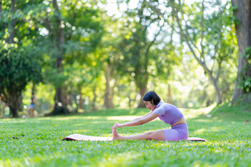 Attractive and strong Asian woman with a beautiful body. yoga in graceful posture in the green park...