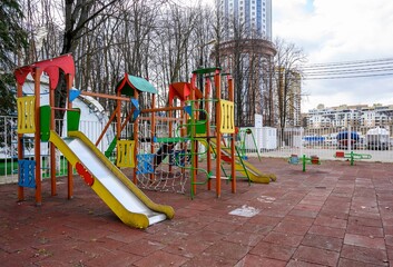 An empty playground in early spring against the background of high-rise buildings