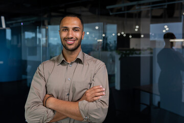 Portrait of hispanic successful businessman, successful man in shirt looking at camera with crossed...