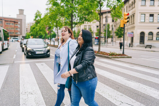 Happy LGBT women walking on zebra crossing and smiling