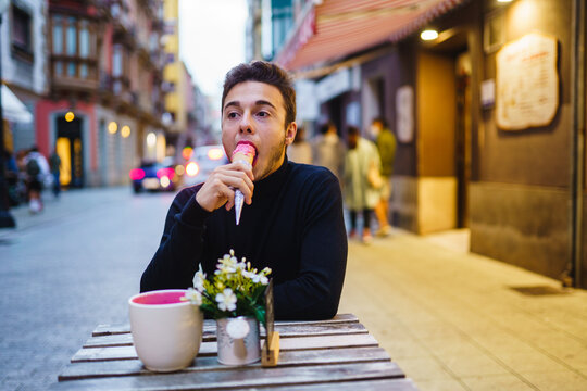 Young Guy Biting Ice Cream On Terrace In City