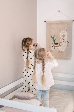 Two girls taking a photo of a wall patchwork art wall of a llama