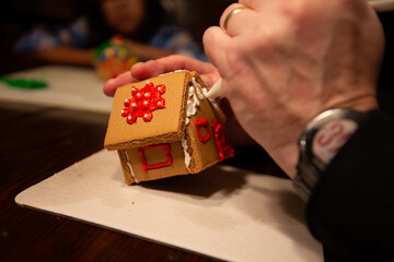 Man's hand decorating a Christmas gingerbread house