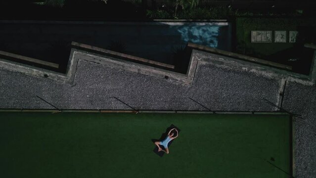 Woman practice yoga on roof, drone fly up,top view