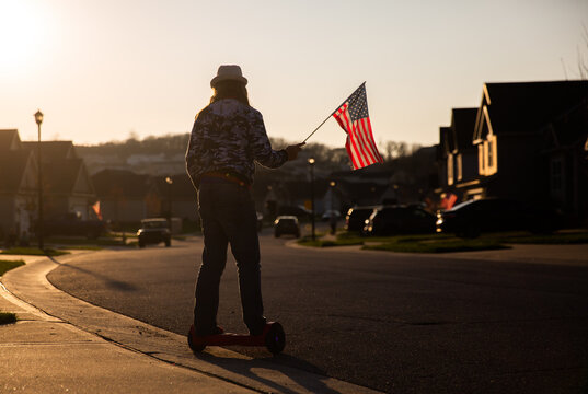 boy riding a hover board while holding American flag