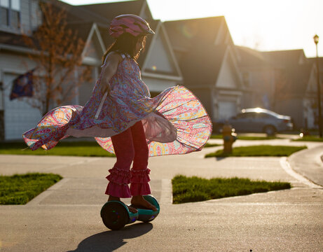 Girl in long flowing dress on a hoverboard in driveway 