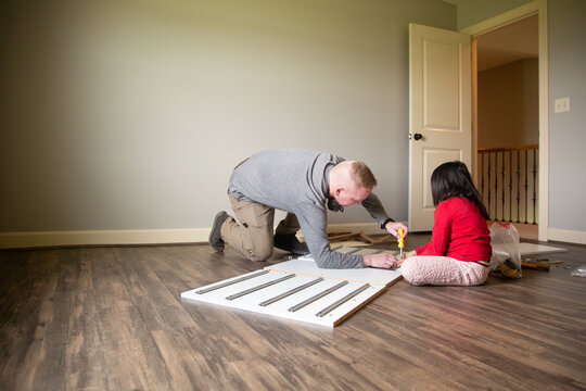 Father and daughter building a wooden rail system unit