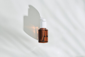 Brown bottle with natural organic cosmetic product under the shadow
