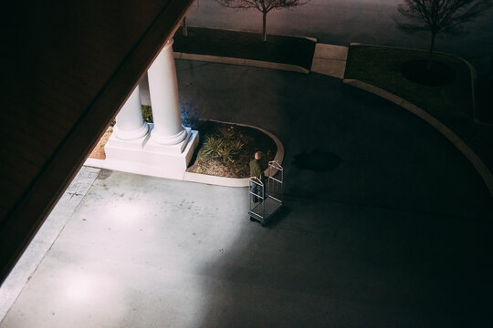 Man Pulling A Hotel Luggage Cart In Parking Lot