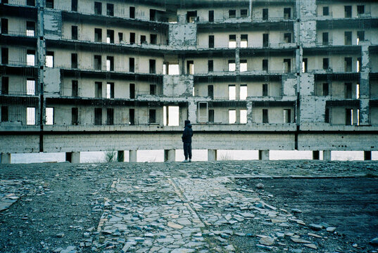 Anonymous man in front of an abandoned building