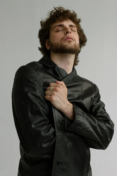 Bearded guy with curly hair got inspired in a  leather black coat 
