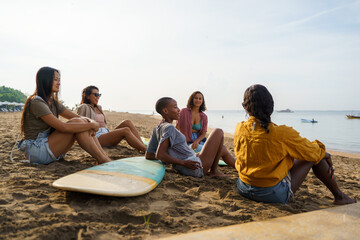 Group of friends with surfboard relaxing on sea shore at beach 