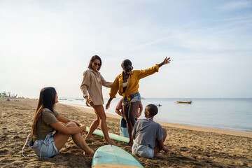 Female friends learning to surf at beach with sky in background