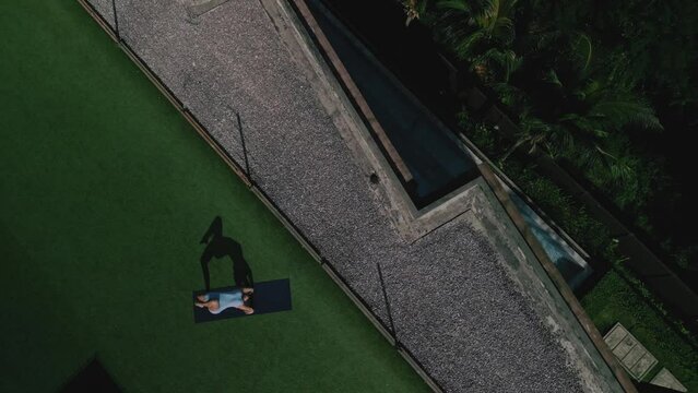 Woman practice yoga on roof, drone fly up,top view
