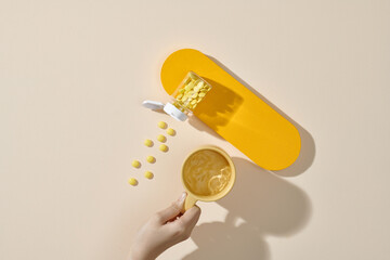 Female hand holding a cup of water and scattered vitamins pills