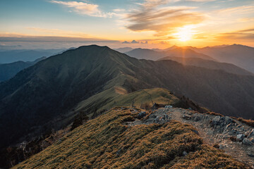 Mountain ridge under cloudy sky at sunset