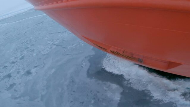 Icebreaker nose on thin ice. Surface of ice broken by ship, splashes of water and pieces of ice
