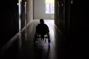 silhouette of person on wheelchair in hallway