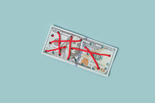 Hundred dollar bill stitched with red threads.