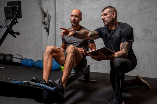 Trainer controlling sportsman on rowing machine