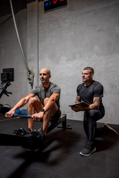 Trainer controlling sportsman on rowing machine