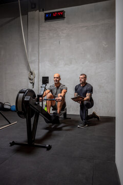 Trainer controlling sportsman on rowing machine