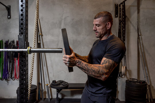 Sportsman putting weight plate on barbell