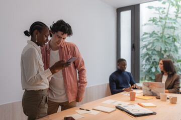 Diverse colleagues using smartphone during break