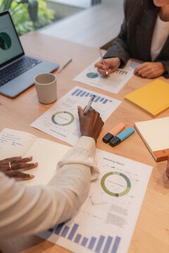 Crop businesswomen making notes on charts