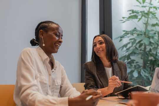 Diverse businesswomen laughing at joke during work