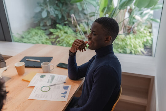 Cheerful black manager sitting at table