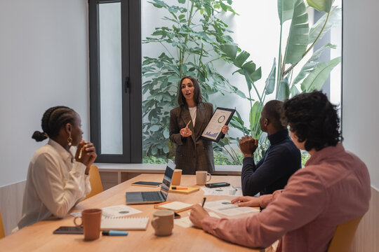 Businesswoman discussing financial report with team - Powered by Adobe