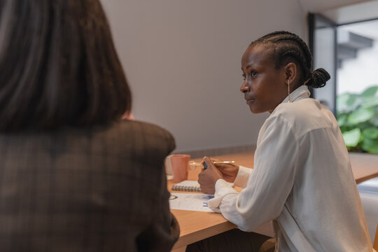 Black manager looking away and listening to colleague