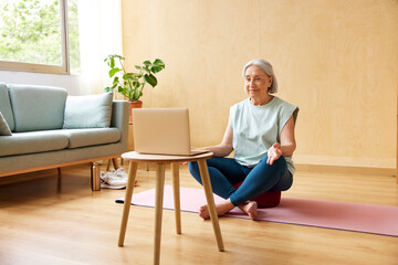 Senior woman having online yoga lesson