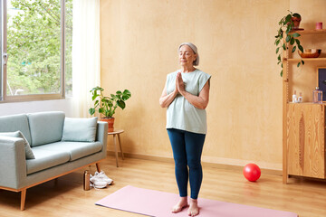 Mature woman meditating in room
