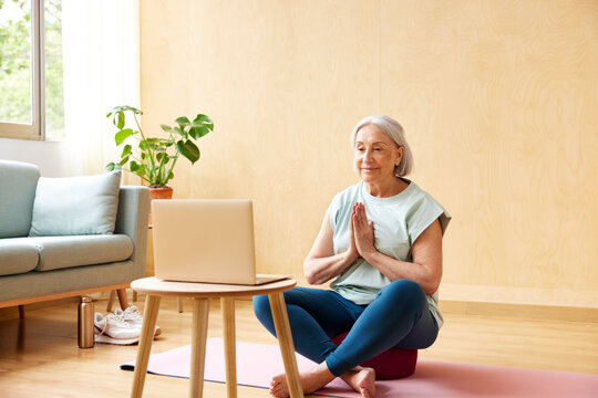 Senior woman meditating during online yoga lesson