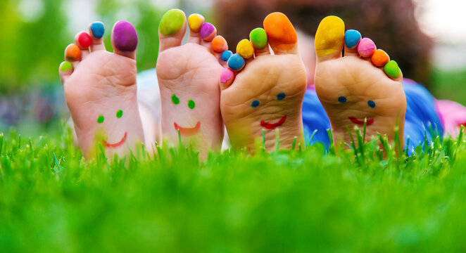 Children's feet with a pattern of paints smile on the green grass. Selective focus.