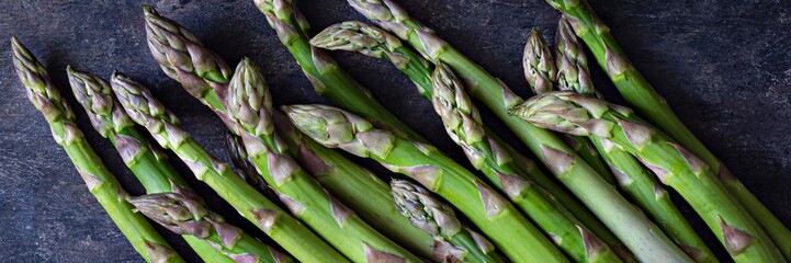 Green asparagus on a dark background. Raw food concept. The vegetable is rich in fiber, a natural...